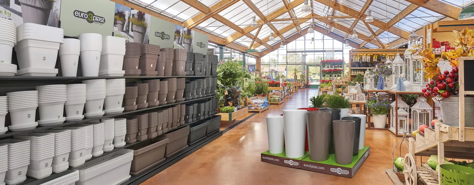 Gartencenter mit euro3plast-Regalwand in Weiß, Taupe und Anthrazit und Palettencover mit hohen Pflanzgefäßen im Mittelgang